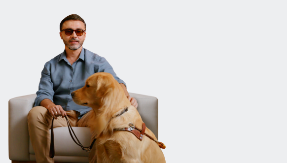 Vision-impaired man with an inherited retinal disease (IRD) sitting with guide dog